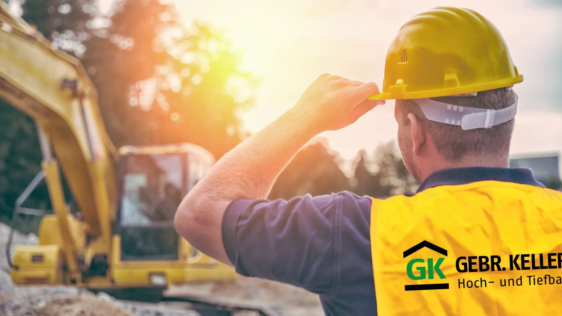 Bauarbeiter mit gelbem Helm und Warnweste vor Bagger bei Sonnenuntergang auf Baustelle